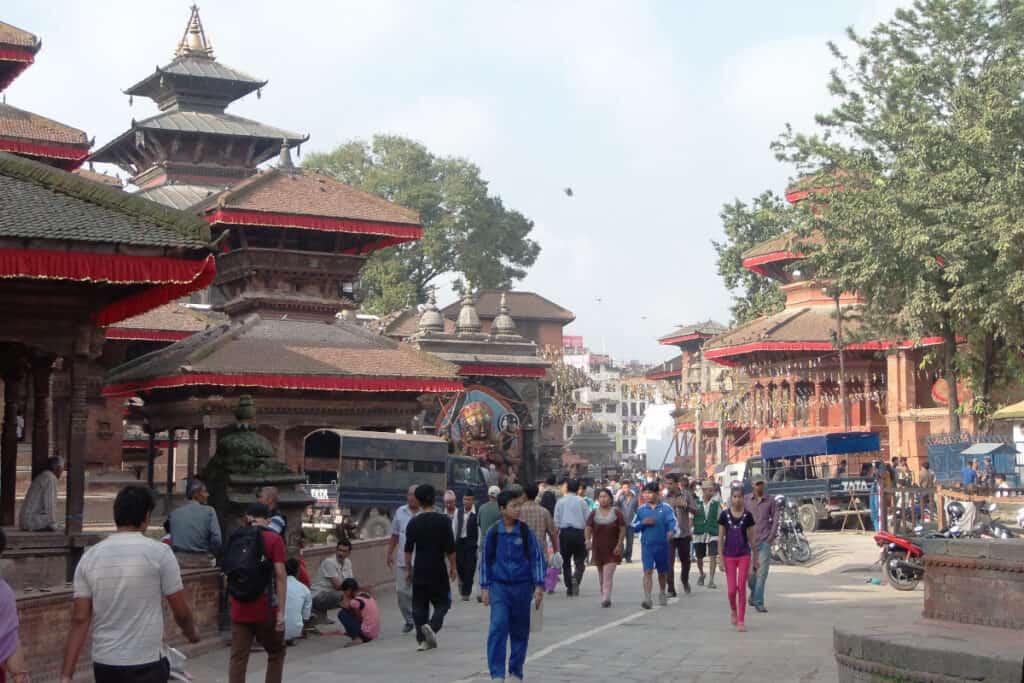 Straßenszene in Kathmandu mit traditionellen Tempeln und Menschen im Alltag – ein lebendiges Bild Nepals