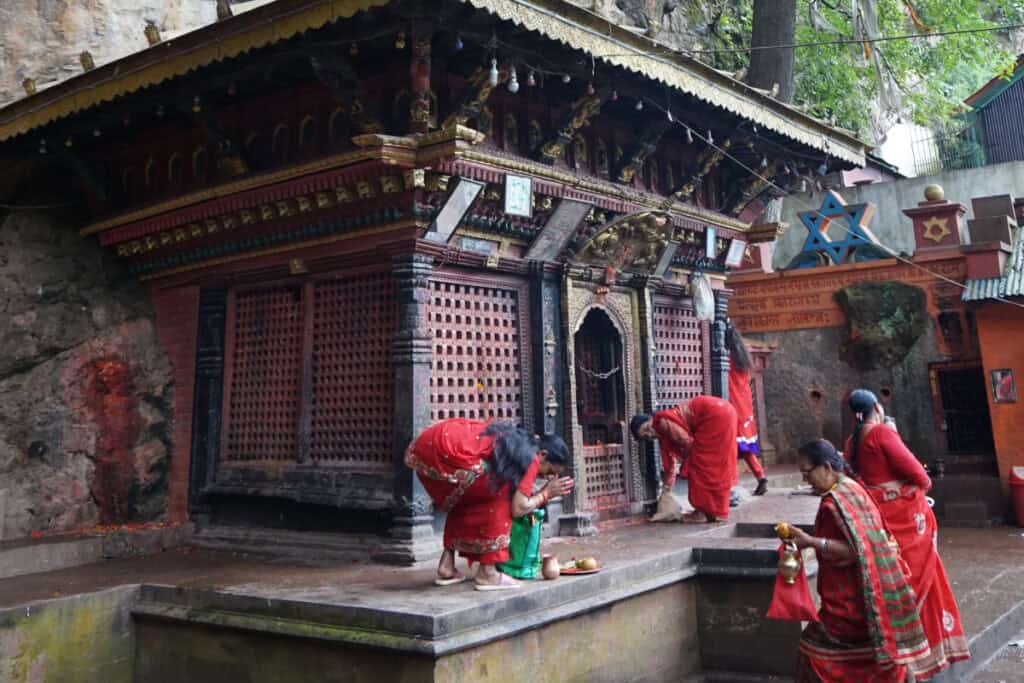 Nepalesische Frauen in roten Saris beim Gebet an einem Tempel – Ausdruck von Tradition und Spiritualität