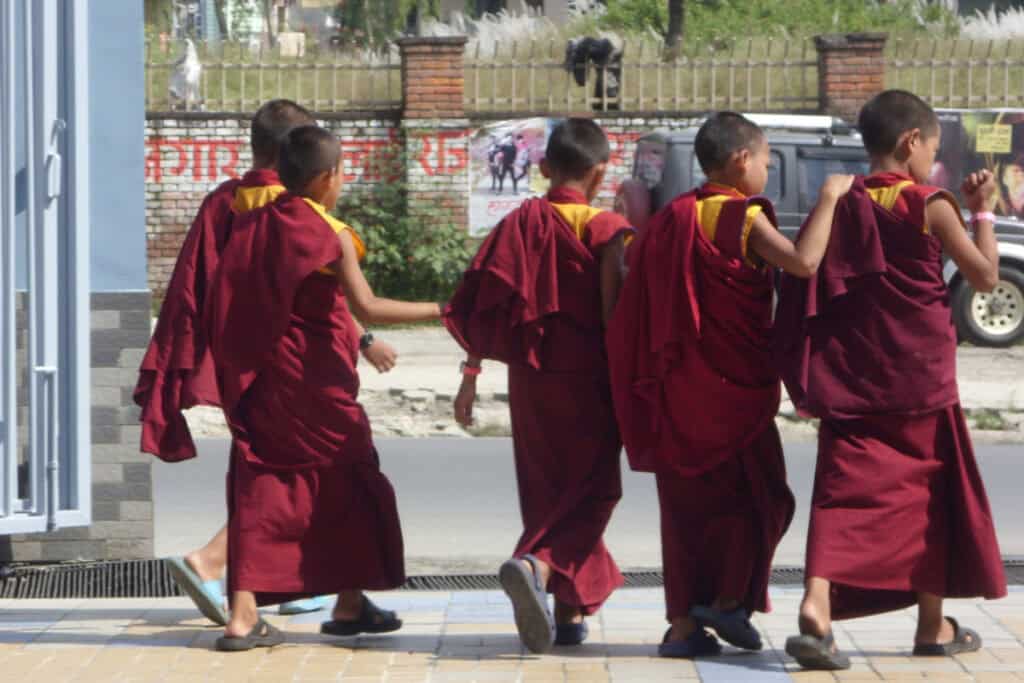 Gruppe junger buddhistischer Mönche in roten Kutten auf dem Weg durch die Straßen in Nepal