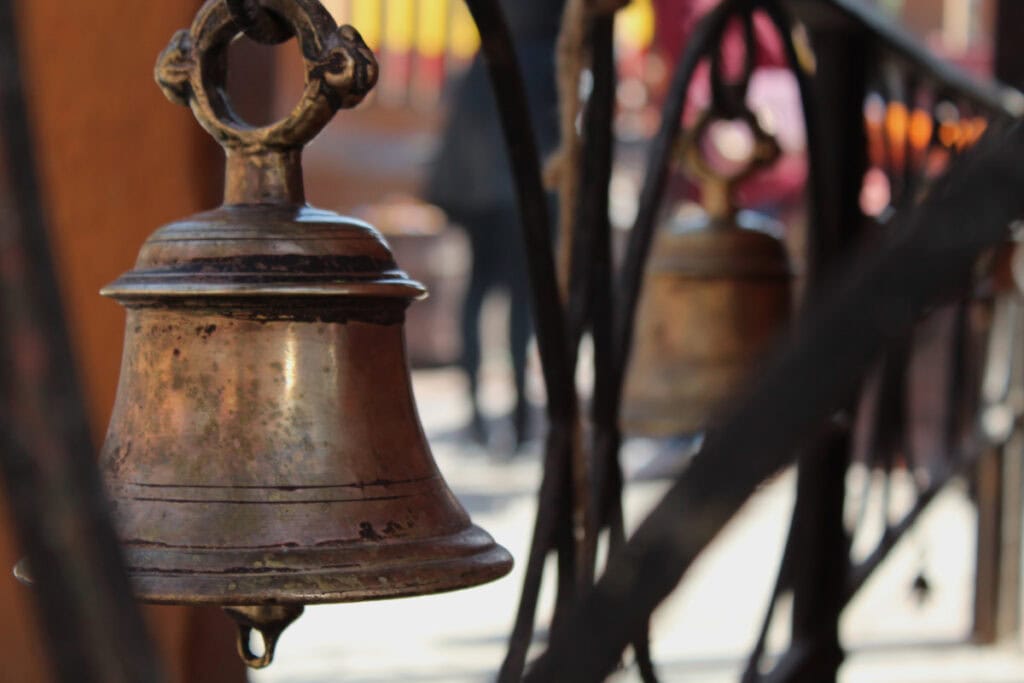 Bronzene Tempelglocke in Nepal im Sonnenlicht – Symbol für die Verbindung von hinduistischen und buddhistischen Traditionen, die sich auch in den verschiedenen Kalendersystemen des Landes widerspiegeln.