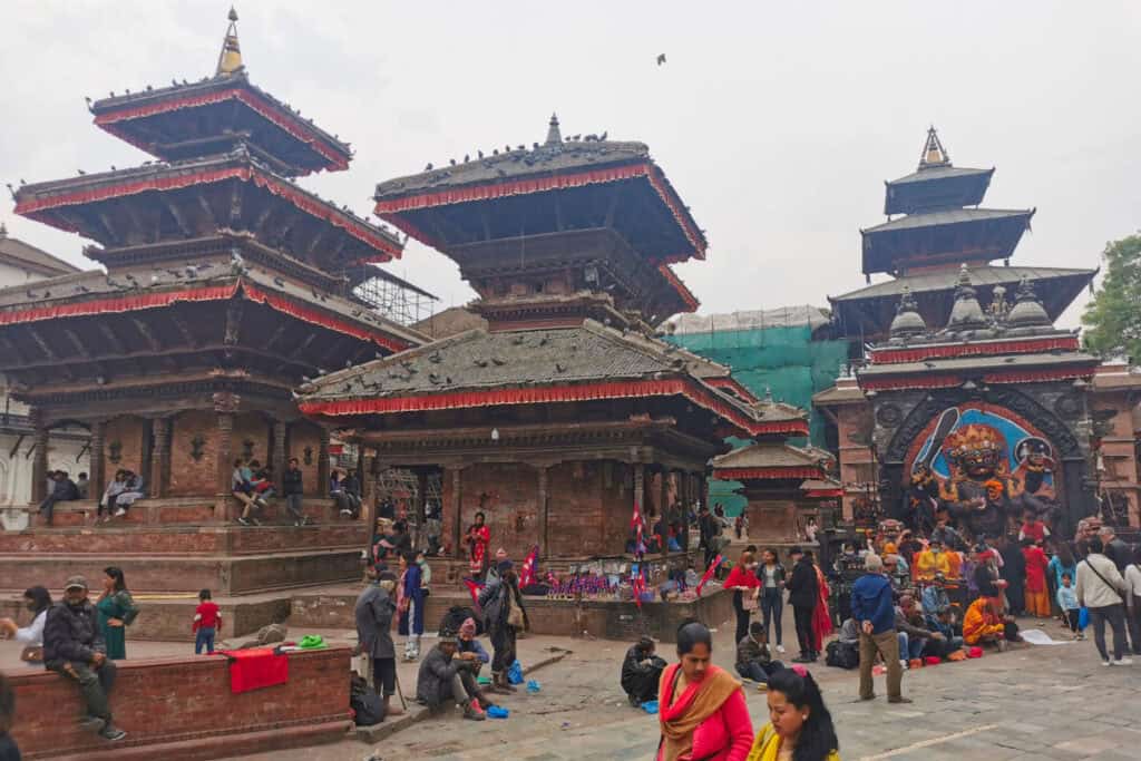 Historische Tempel am Kathmandu Durbar Square mit Newar-Architektur und Kal Bhairav, umgeben von Menschen im Alltag.