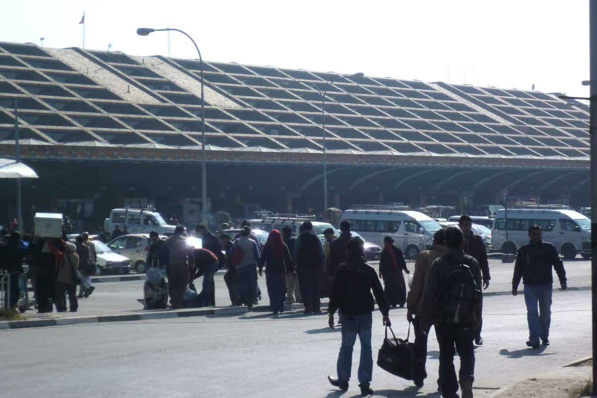 Reisende mit Gepäck vor dem internationalen Flughafen in Kathmandu – viele Nepalesinnen und Nepalesen verlassen das Land, um im Ausland zu arbeiten.