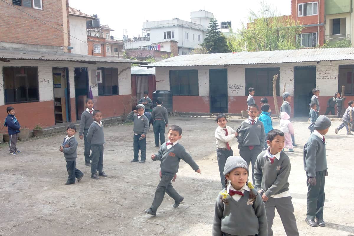 Kinder in Schuluniform auf einem Pausenhof einer nepalesischen Schule – eine typische Szene aus dem städtischen Bildungssystem.