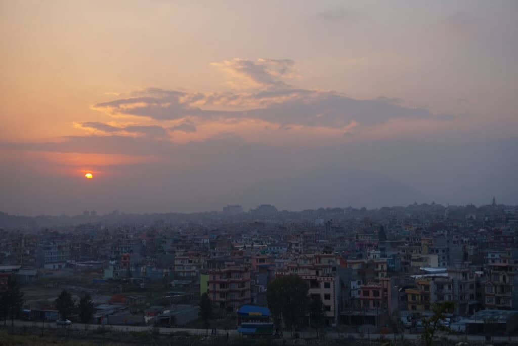 Sonnenuntergang über der dicht bebauten Stadt Kathmandu – ein Sinnbild für Nepals politischen und gesellschaftlichen Wandel im 20. und 21. Jahrhundert.