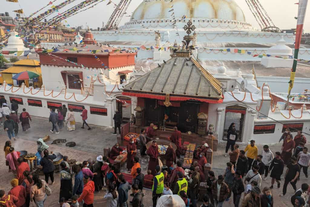 Menschen, Mönche und Besucher rund um die Boudha-Stupa in Kathmandu – Tempel und Stupa als gelebter Ort im Alltag.