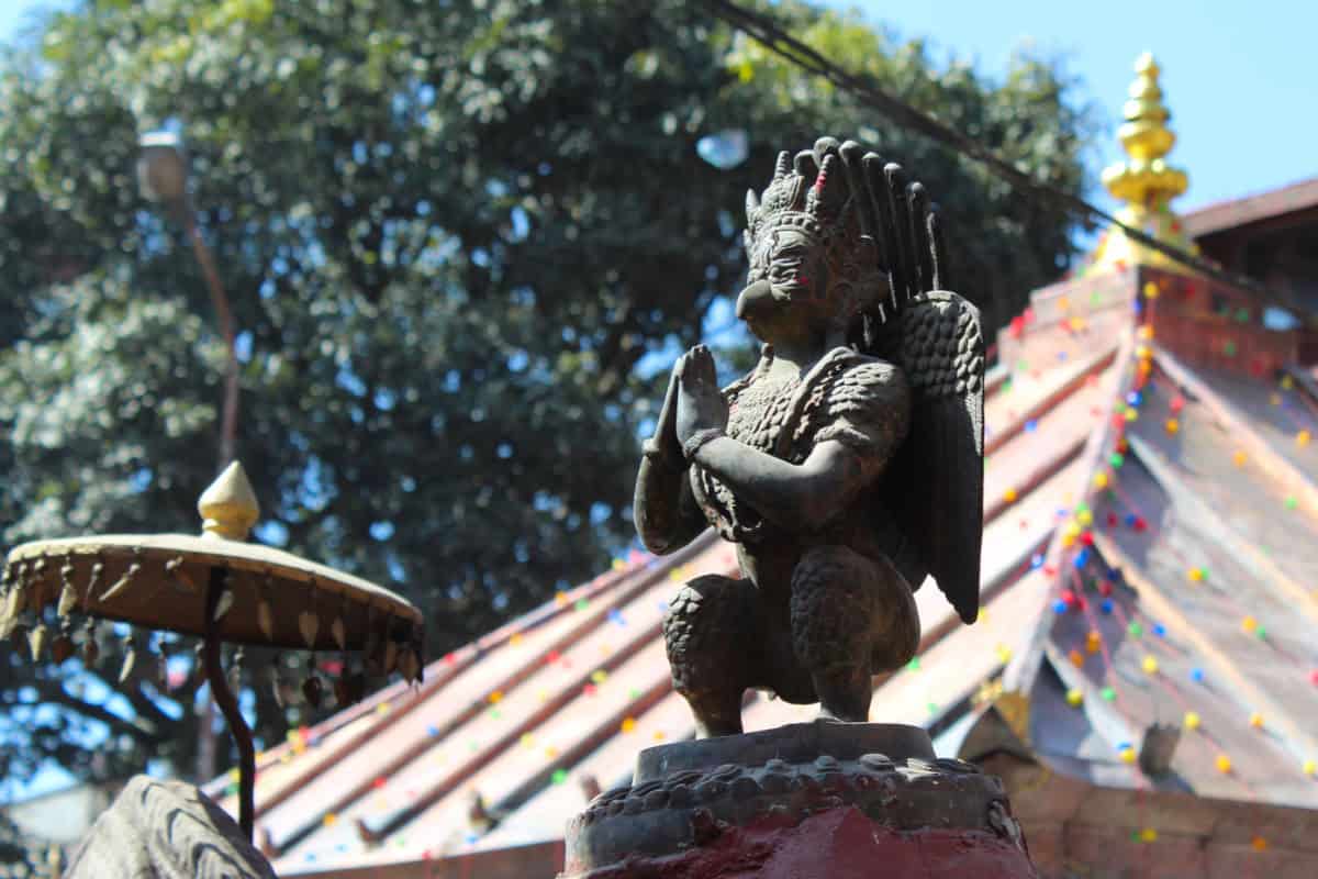 Hinduistische Gottheit in Gebetshaltung vor einem Tempel in Nepal – Hinduismus als Teil des gelebten Alltags.