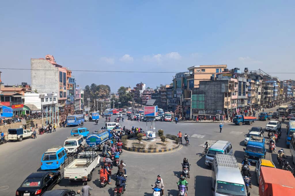 Dichter Verkehr an einem großen Straßenknotenpunkt in Kathmandu mit Bussen, Motorrädern und Autos