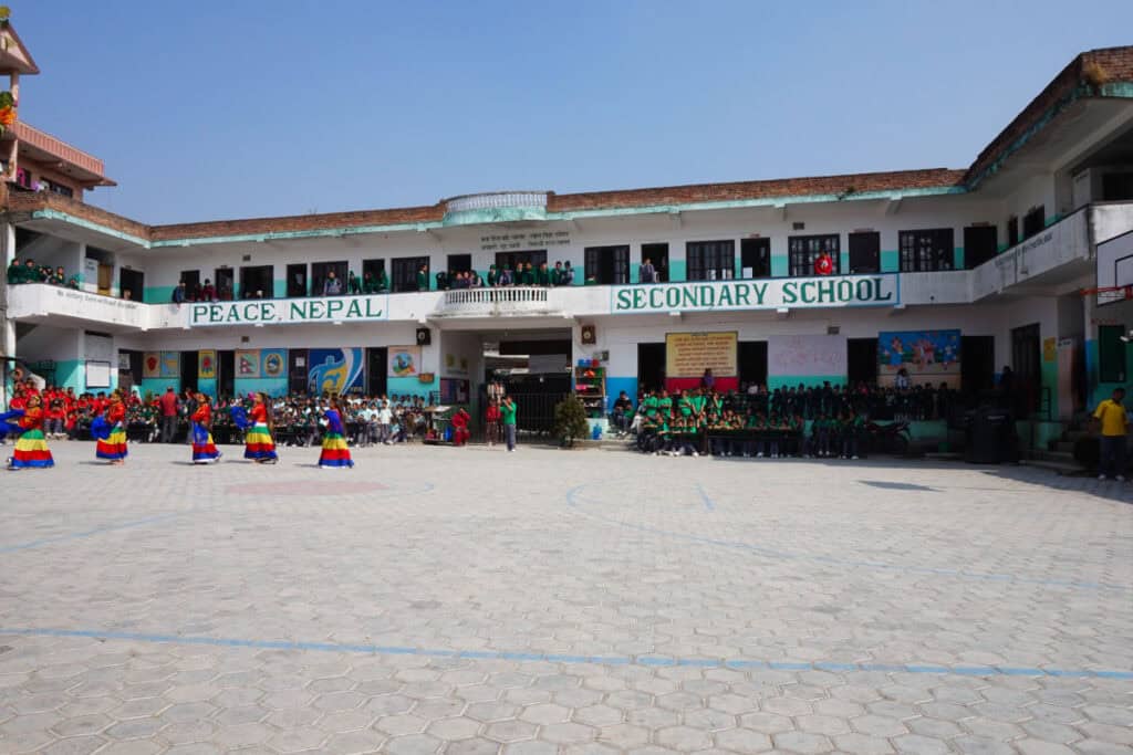 Schulhof einer privat geführten Schule in Nepal mit Schülerinnen und Schülern während einer Veranstaltung.