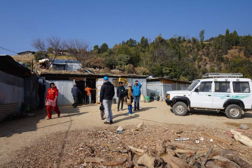Zwischenstopp in einem nepalesischen Dorf mit Jeep und wartenden Menschen während einer Reise