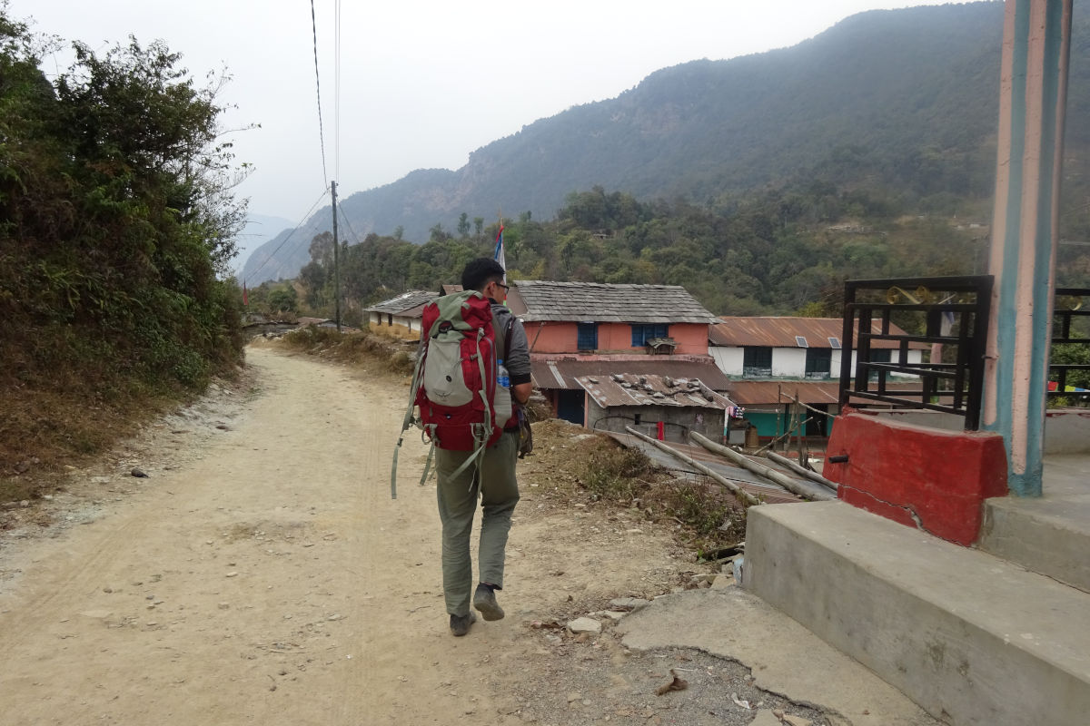 Reisender mit Rucksack auf einem Dorfweg in Nepal