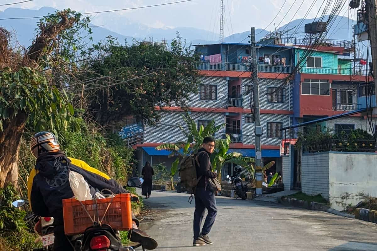 Alltagsszene in Nepal mit Motorradfahrer und Fußgänger in ruhigem Wohnviertel