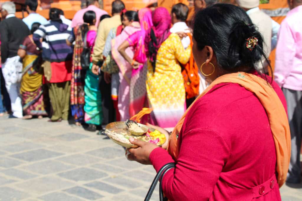 Frau mit Opfergabe vor einem Tempel in Nepal – religiöse Praxis als selbstverständlicher Teil des Alltags.