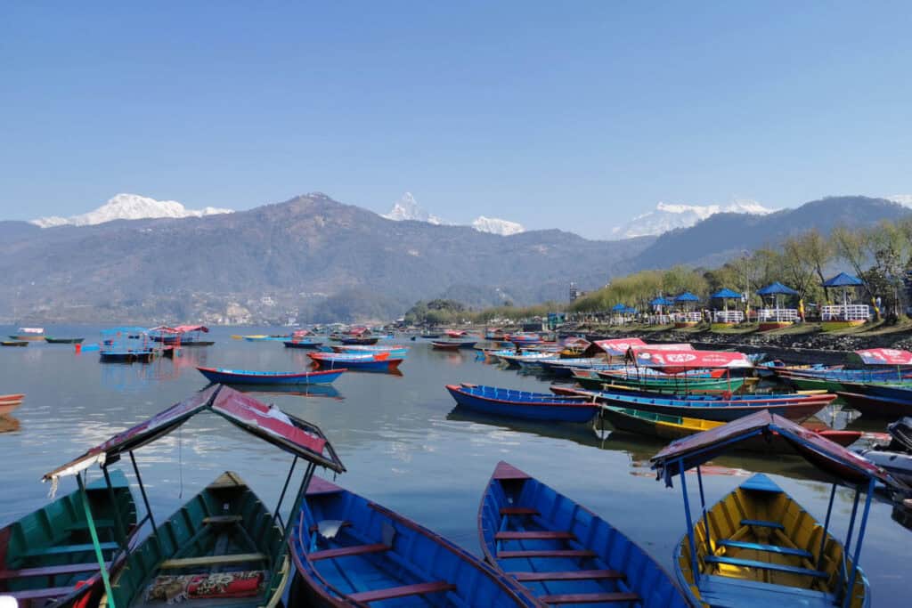 Bunte Boote am Ufer des Phewa-Sees in Pokhara vor den Bergen des Annapurna-Massivs