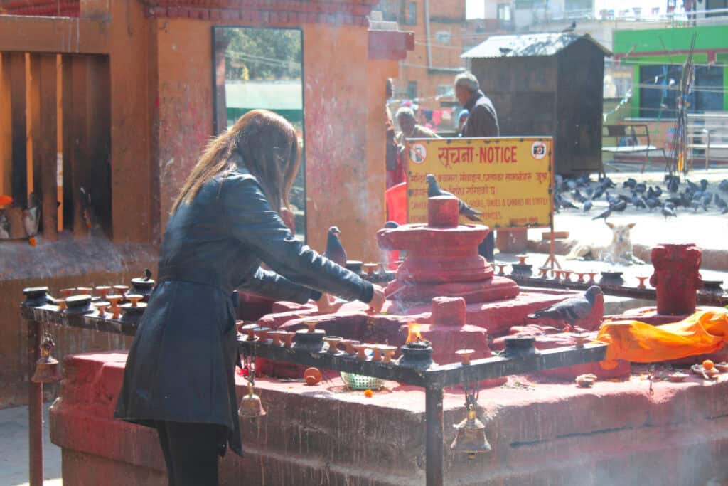Nepalesin entzündet Butterlampen an einem Tempel in Kathmandu – religiöse Rituale als selbstverständlicher Teil des Alltags.