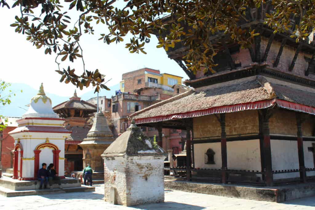 Menschen sitzen in einem Tempelhof im historischen Kathmandu-Tal