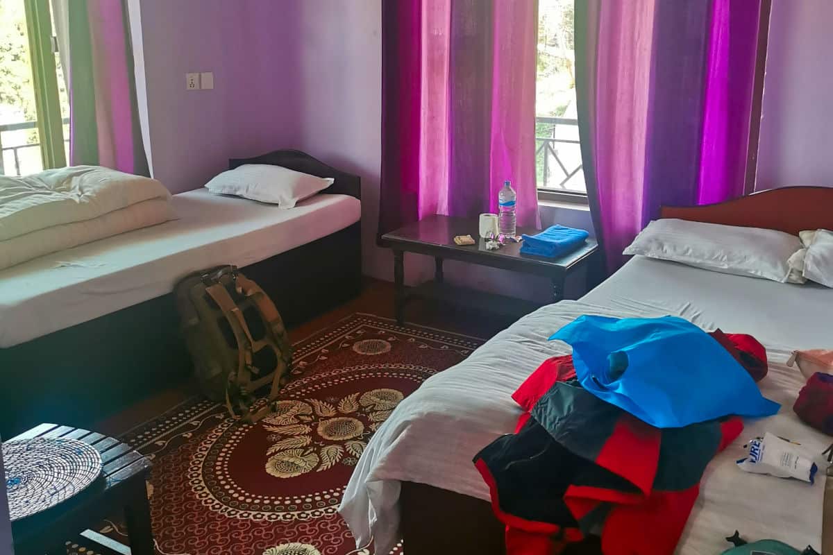 Einfaches Gästezimmer in Nepal mit zwei Betten und Reisegepäck