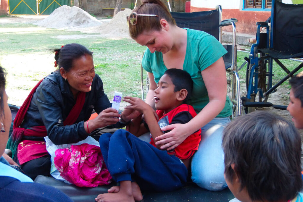Freiwilligenarbeit in Nepal – Zusammenarbeit mit Project Volunteer Nepal Volunteer und lokale Mitarbeiterin arbeiten gemeinsam mit einem Kind in einer Behindertenschule in Nepal