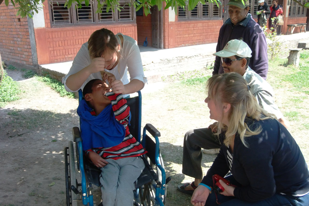 Erfahrene Freiwillige unterstützt ein Kind an einer Behindertenschule in Nepal
