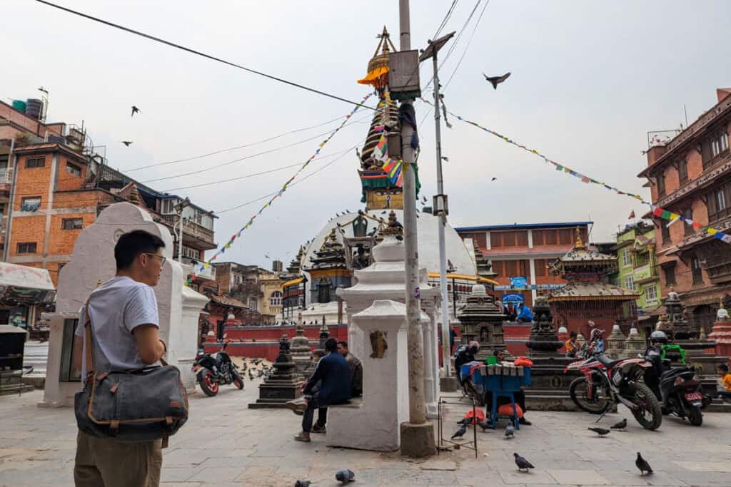 Offener Platz mit kleinem Stupa im Viertel Ason in Kathmandu, Menschen sitzen, trinken Tee und ruhen sich aus