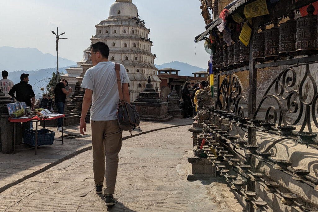Khai-Thai auf einem Tempelweg in Nepal zwischen Gebetslampen und Stupa