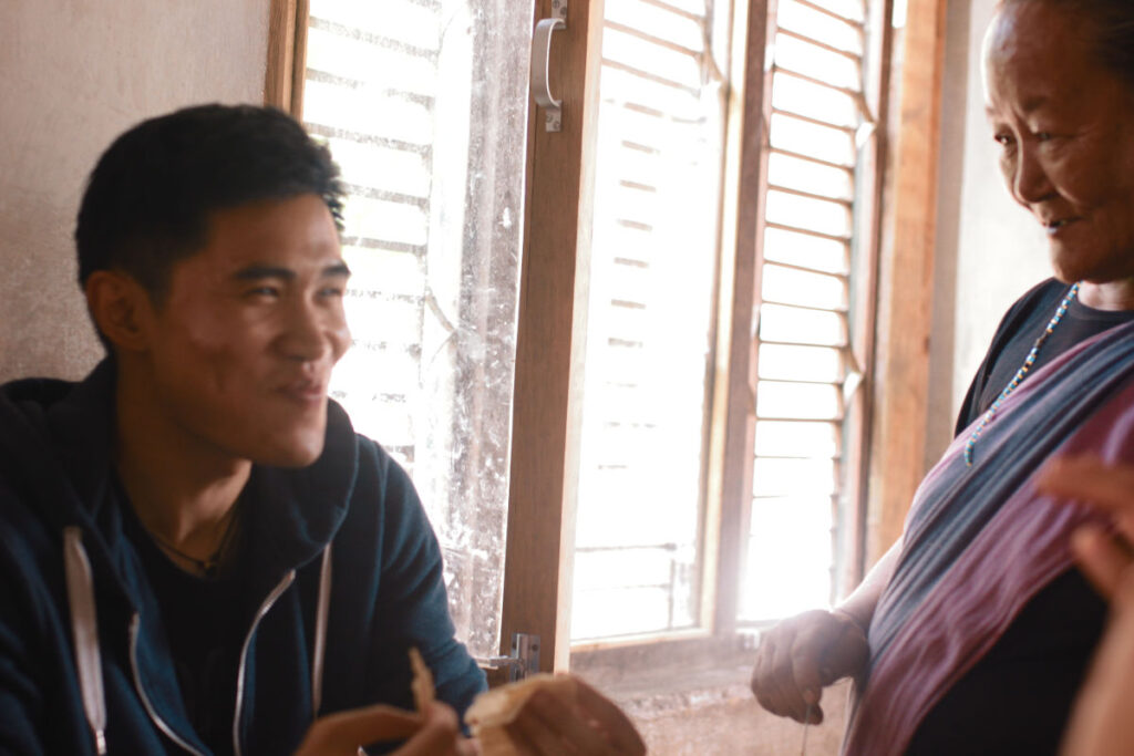 Khai-Thai im Gespräch mit einer älteren nepalesischen Frau in einem Haus am Fenster