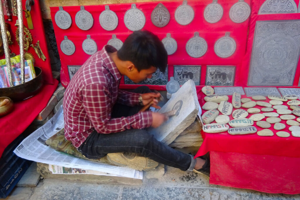Steinmetz in Nepal bei der Arbeit an einer gravierten Steinplatte