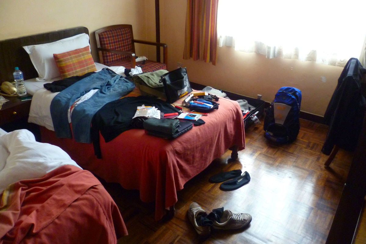 Ausgebreitete Kleidung und Reiseausrüstung in einem Hotelzimmer in Nepal