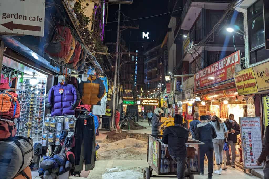 Belebte Straße im Stadtteil Thamel in Kathmandu bei Nacht mit Shops, Hotels und Reisenden