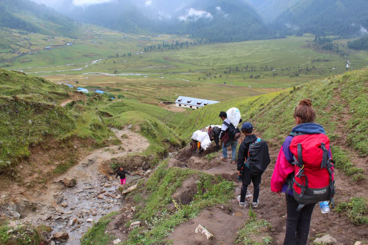 Trekkinggruppe auf schmalem Pfad durch grüne Berglandschaft in Nepal
