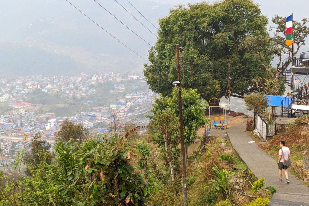 Unterwegs mit Blick über Nepal Khai-Thai geht einen Weg entlang mit Blick auf eine nepalesische Stadt im Tal