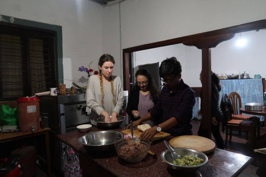 Reisende bereiten gemeinsam Momos in einer Küche eines tibetischen Homestays in Nepal zu