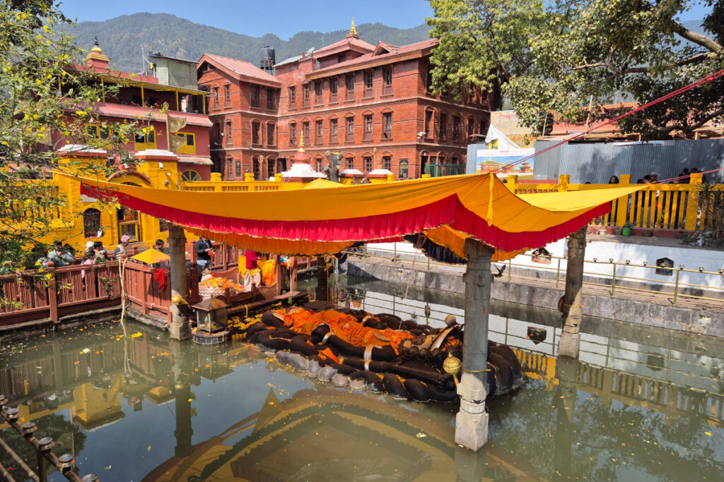Schlafender Vishnu in Budhanilkantha – Gesamtansicht Schlafender Vishnu im Wasserbecken von Budhanilkantha mit Tempelanlage