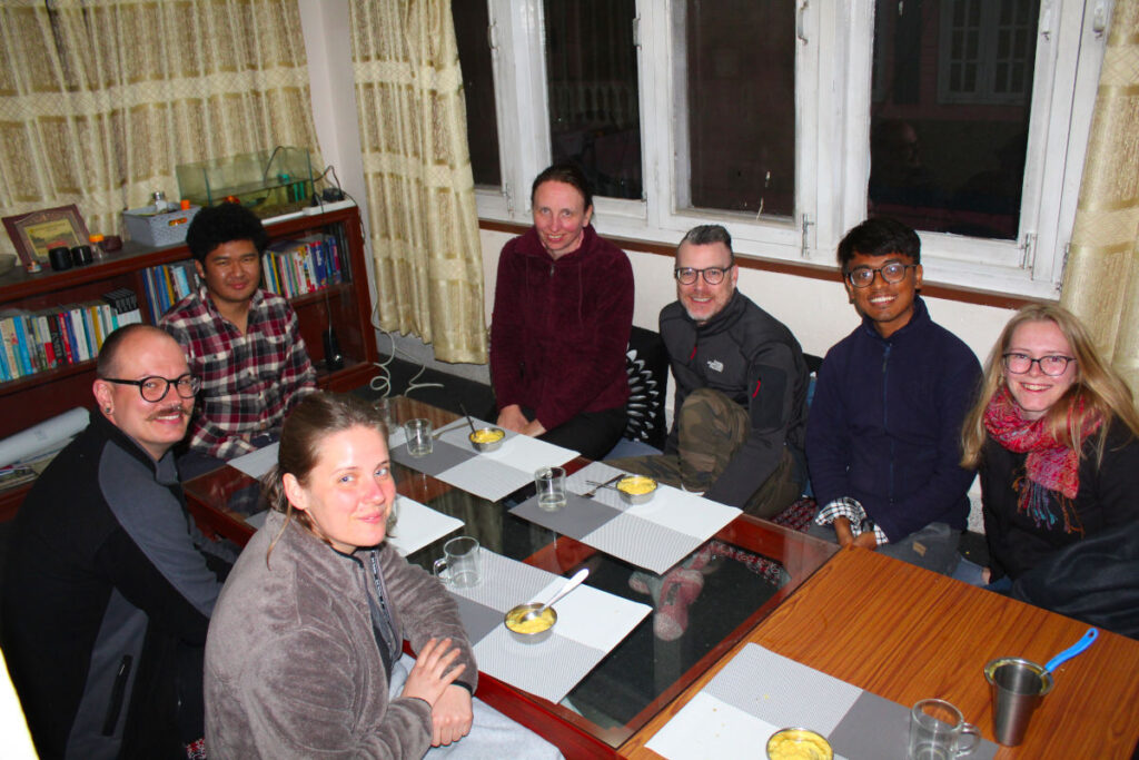 Gruppe sitzt gemeinsam im Wohnzimmer eines Homestays in Kathmandu und verbringt Zeit miteinander