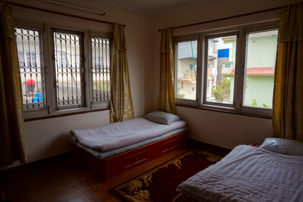Einfach eingerichtetes, helles Schlafzimmer mit zwei Betten im Homestay in Kathmandu