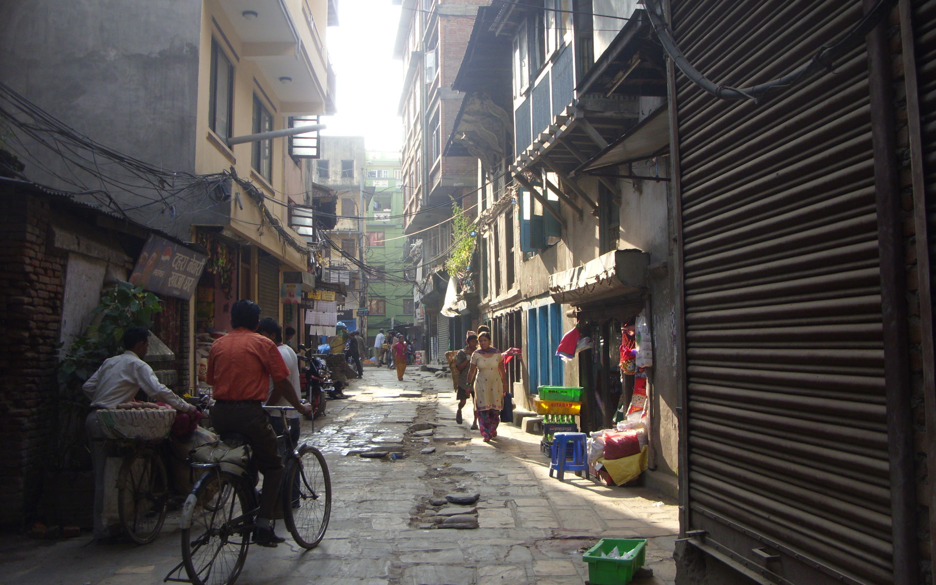 Enge Gasse in Kathmandus Altstadt mit Menschen, Fahrrad und typischer Bebauung