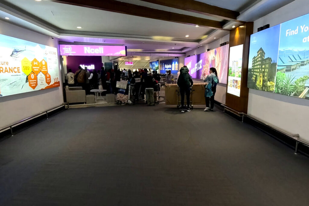 SIM-Karte am Flughafen Kathmandu kaufen Ankunftsbereich am Flughafen Kathmandu mit Ncell Shop und Reisenden