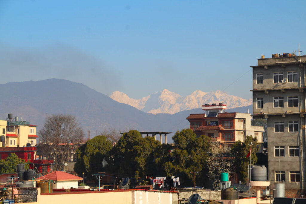 Blick über Kathmandu mit Wohnhäusern und Himalaya im Hintergrund