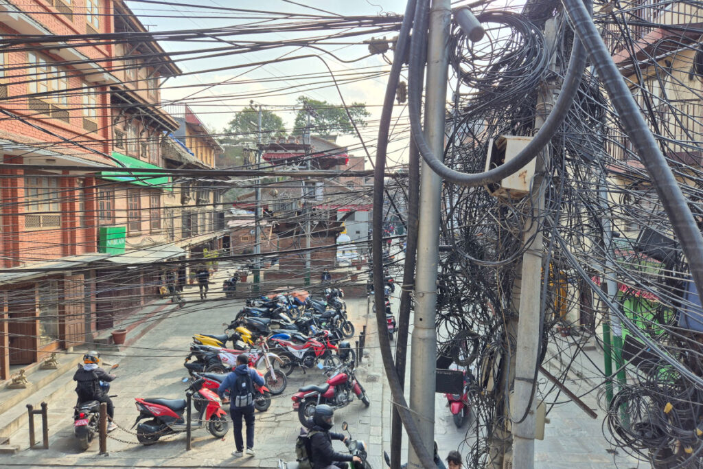 Straßenszene in Kathmandu mit Motorrädern und vielen Stromkabeln