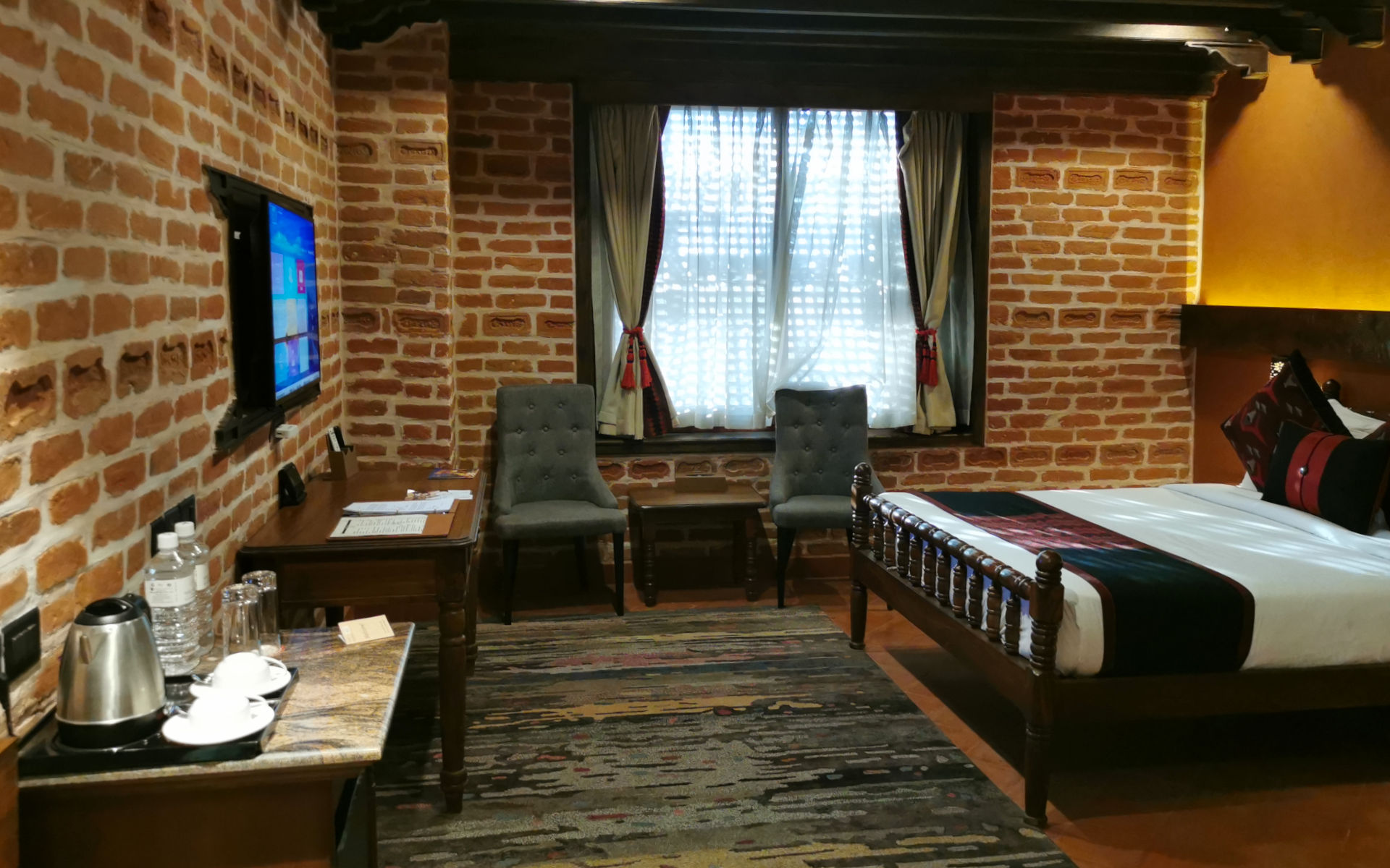 Gemütliches Hotelzimmer in Nepal mit Backsteinwänden, Bett und Sitzbereich