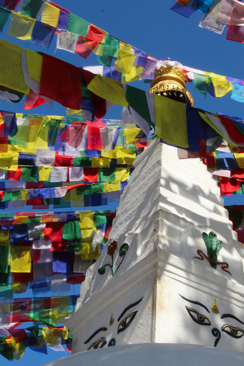 Bunte tibetische Gebetsfahnen über einer weißen Stupa mit Buddha-Augen in Nepal