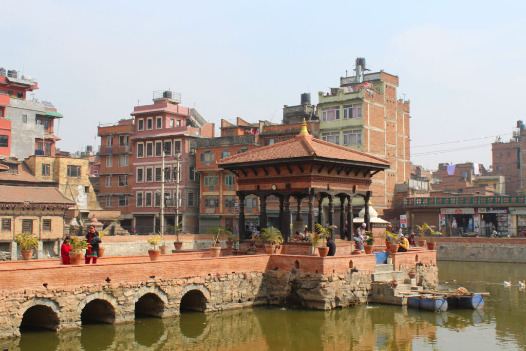 Menschen am Wasserbecken im Patan Durbar Square mit historischer Architektur