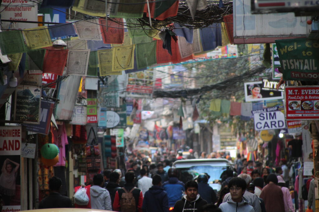 Belebte enge Straße in Thamel mit vielen Menschen, Autos und Geschäften