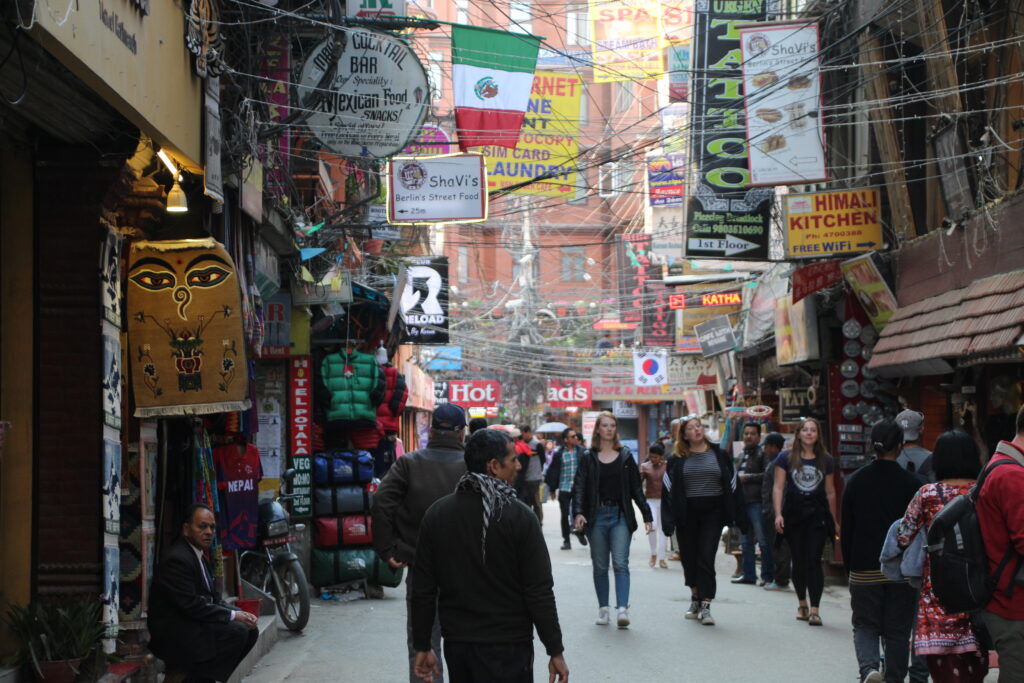 Belebte Gasse in Thamel mit vielen Schildern, Shops und Touristen