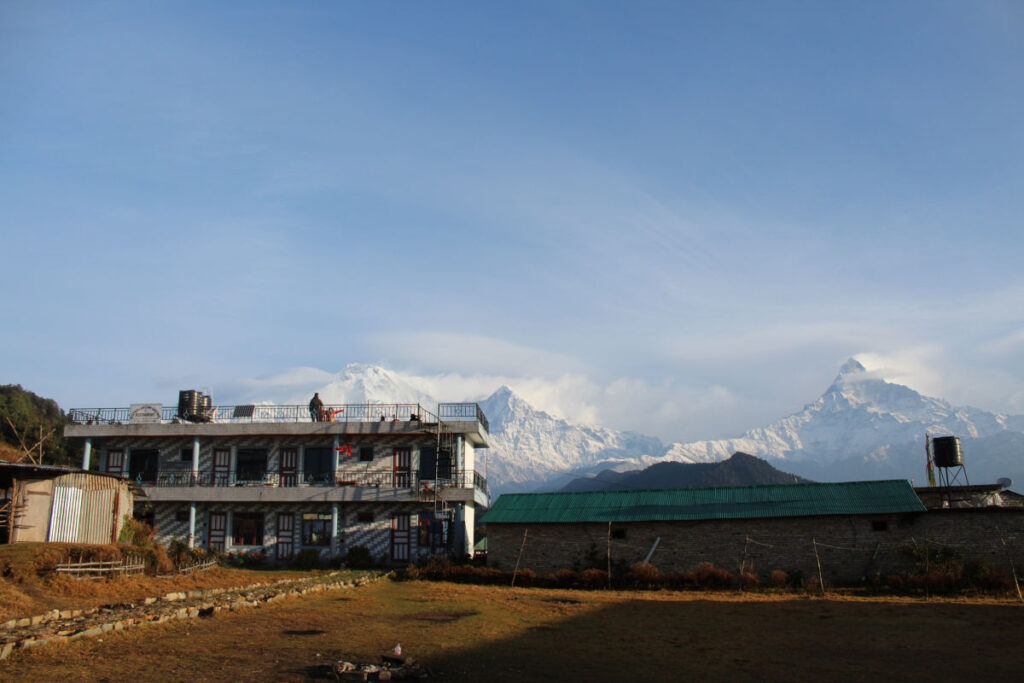 Einfache Lodge in einem nepalesischen Bergdorf mit schneebedeckten Bergen im Hintergrund