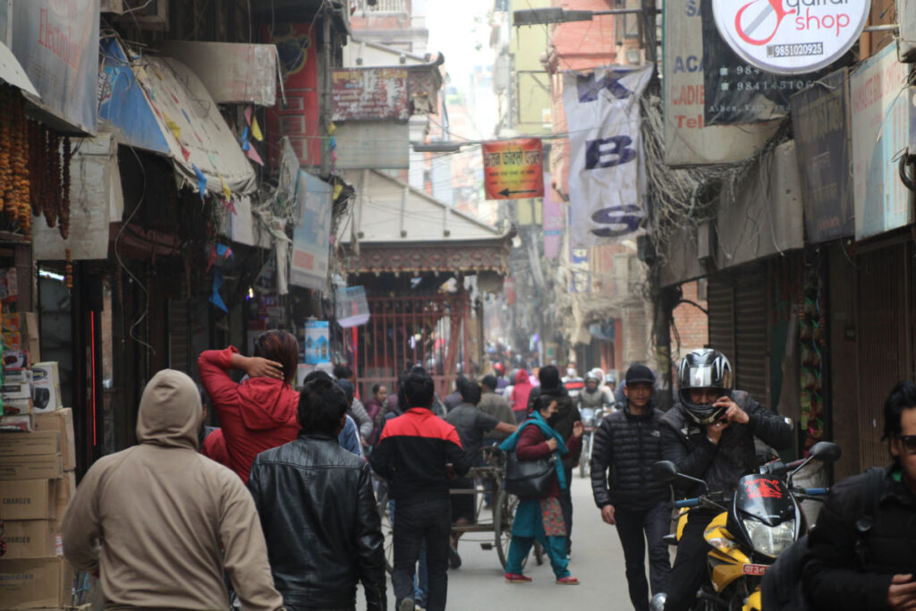 Alltag in Kathmandu zwischen Bewegung und Struktur Belebte enge Straße in Kathmandu mit Menschen, Motorrädern und Geschäften