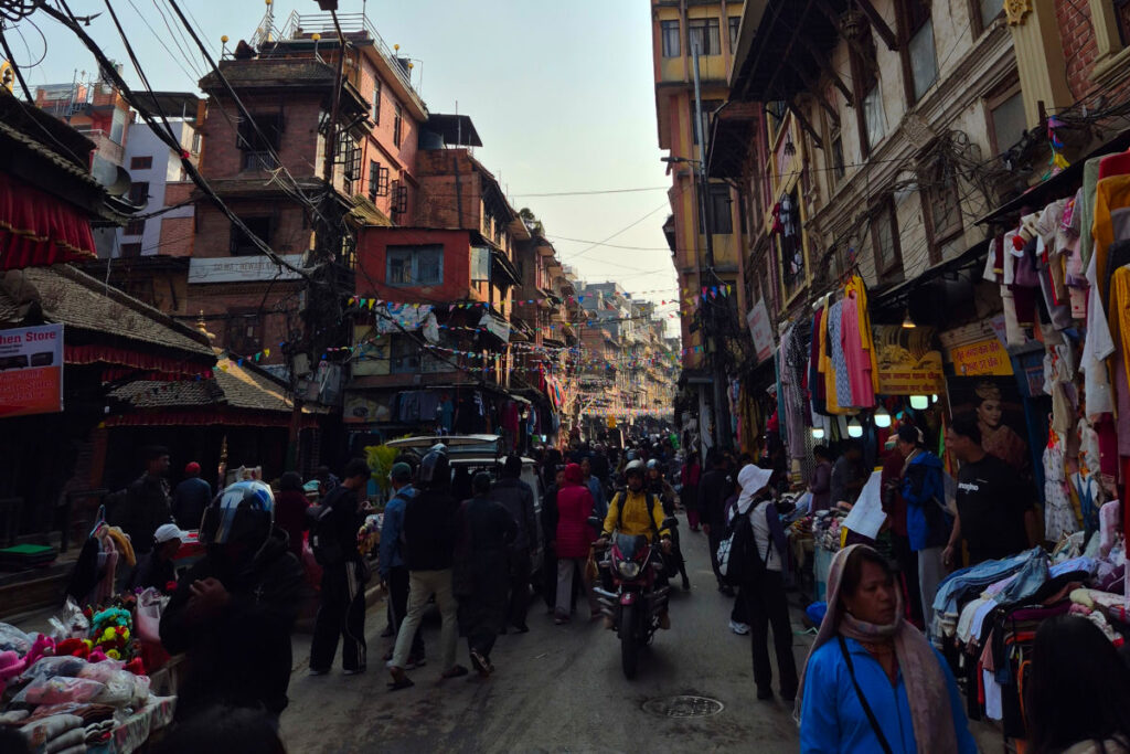 Alltag auf den Straßen von Kathmandu Belebte Straße in Kathmandu mit Menschen, Motorrädern und Marktständen