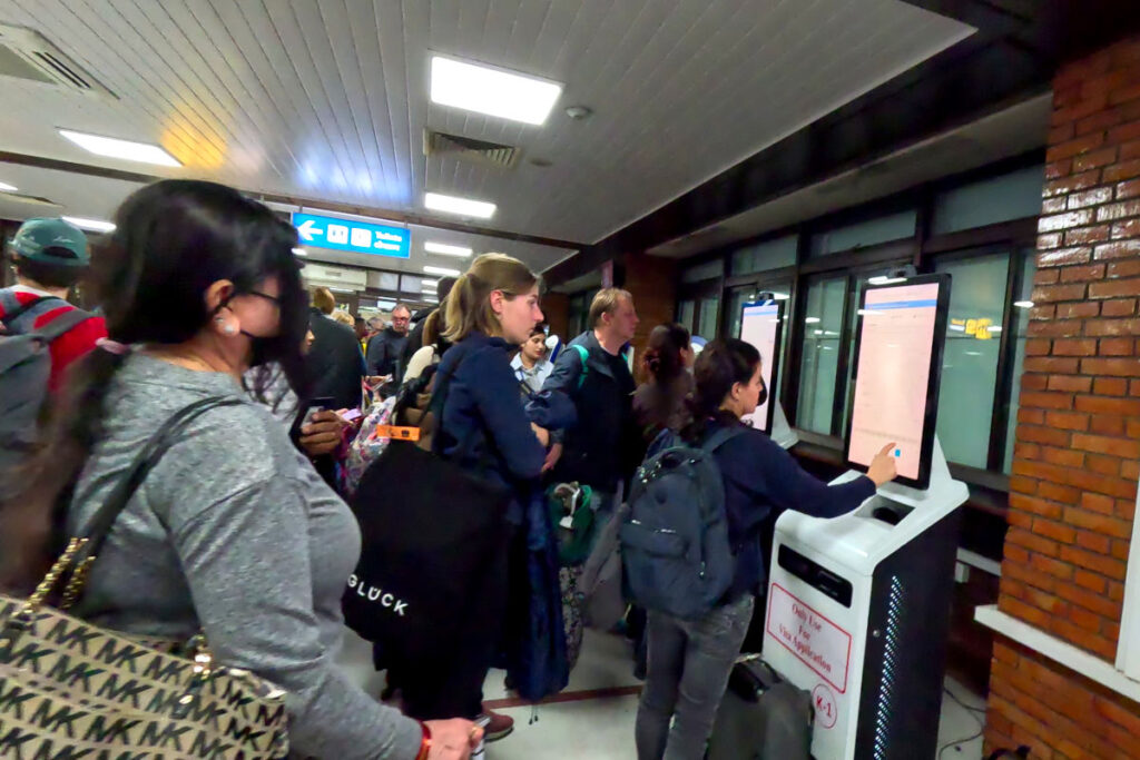 Warteschlange am Visa-Automaten in Kathmandu Reisende stehen am Visa-Automaten am Flughafen Kathmandu und füllen Formulare aus