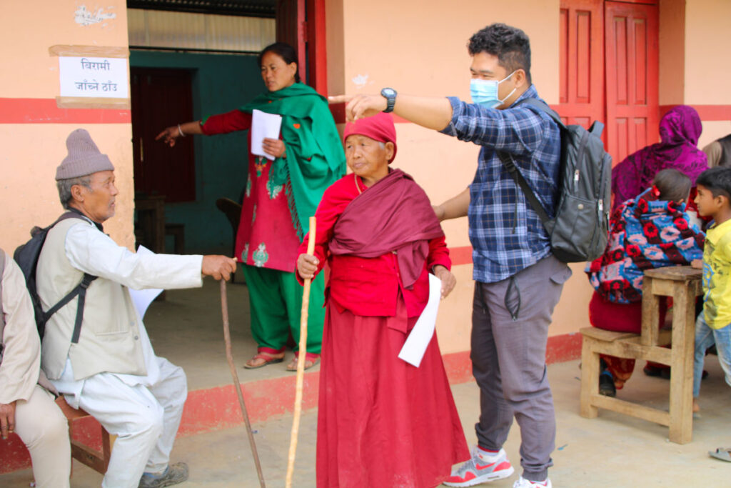Menschen versammeln sich vor einem Gebäude in einem Dorf in Nepal für medizinische Versorgung