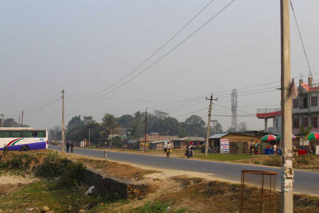 Straße im ländlichen Nepal mit einfacher Bebauung und wenig Verkehr