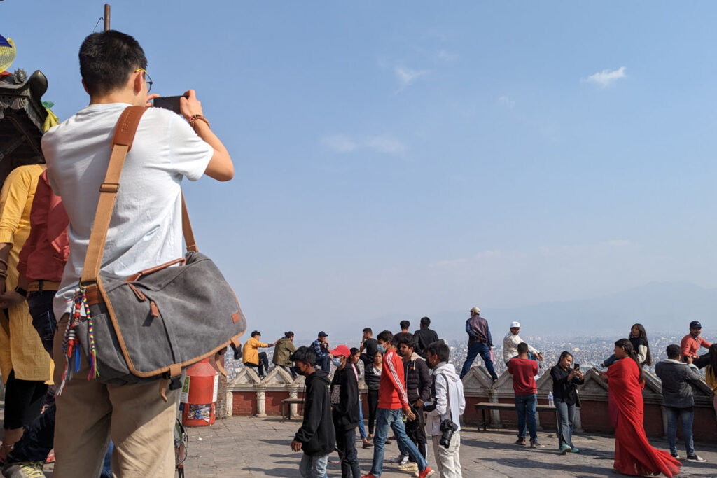 Person fotografiert bei Swayambhunath in Kathmandu zwischen vielen Menschen
